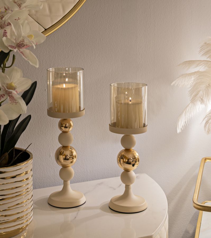 Portacandele GLASSY crema con candele accese su piano in marmo, accanto a uno specchio dorato #colore_Crema