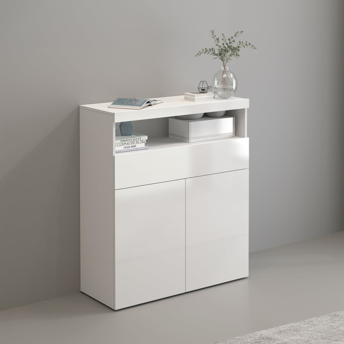 Credenza alta bianco opaco in interno, vano a giorno con libri e vaso di vetro