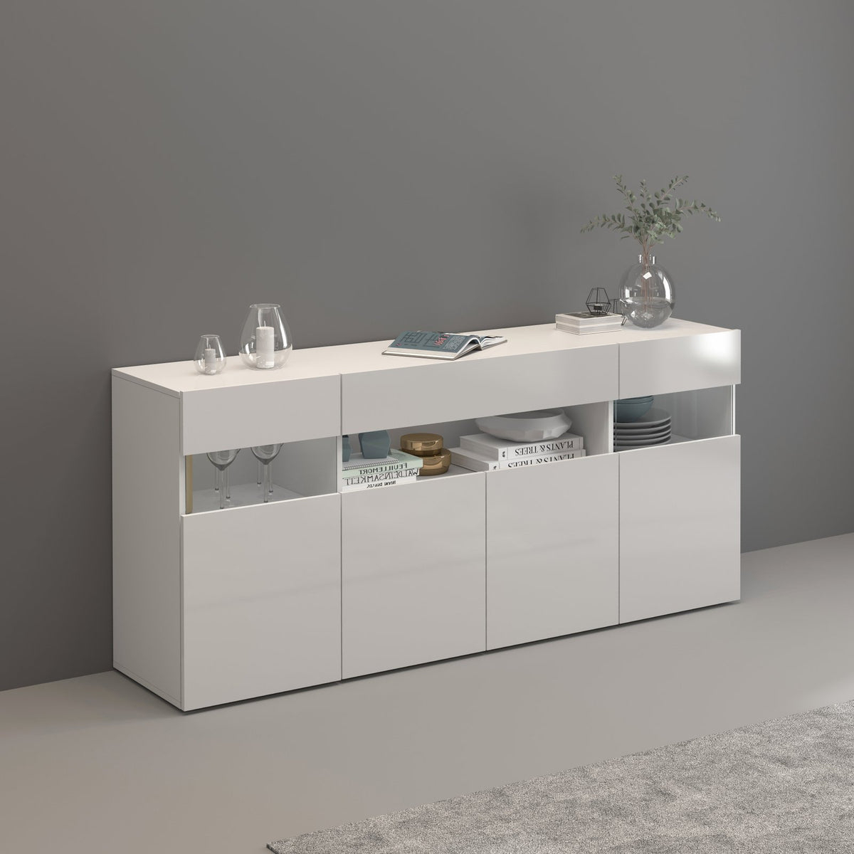 CREDENZA BASSA bianco opaco con ante lucide, vani a giorno e oggetti di scena sul piano
