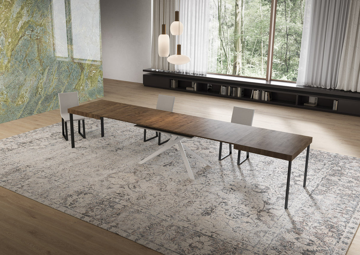 Tavolo NIKET effetto noce allungato con base centrale a X bianca, in soggiorno con tre sedie #colore_Noce