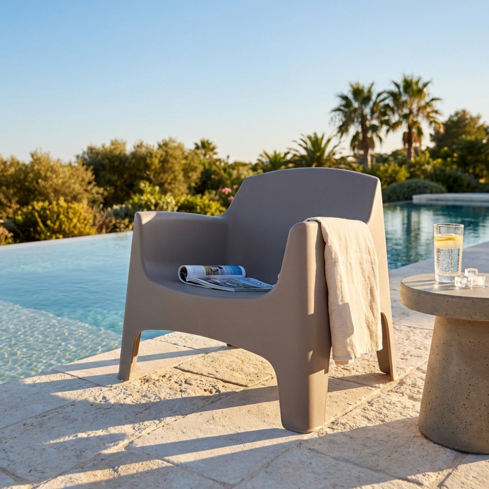 Poltrona IBIZA taupe ambientata in giardino con telo sul bracciolo e rivista sulla seduta