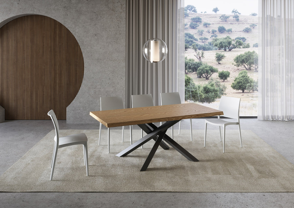 Tavolo VERSALUX rovere con gambe incrociate antracite in interno con finestra su paesaggio collinare