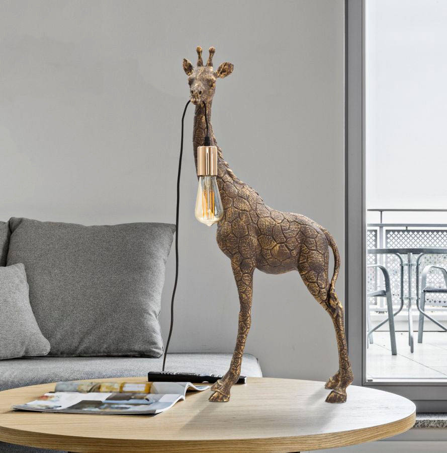 Lampada GIRAFFA oro accesa su tavolino in legno in salotto con divano e vetrata sullo sfondo #dimensione_40x80x22
