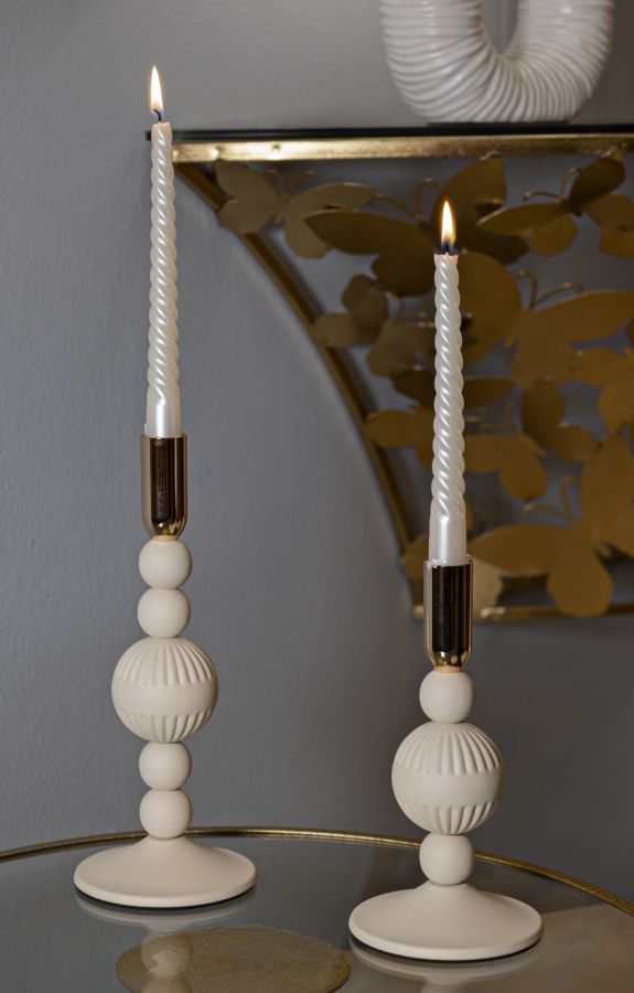 Portacandele ASTER crema con candele accese posati su un piano rotondo in ambiente interno #colore_Crema