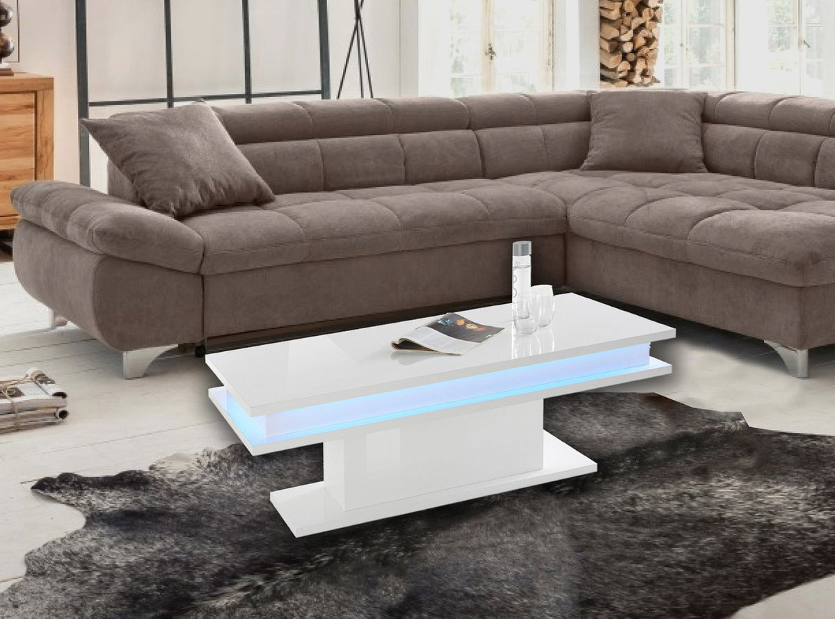 Tavolino da salotto EOS bianco lucido con LED blu sotto il piano, davanti al divano taupe