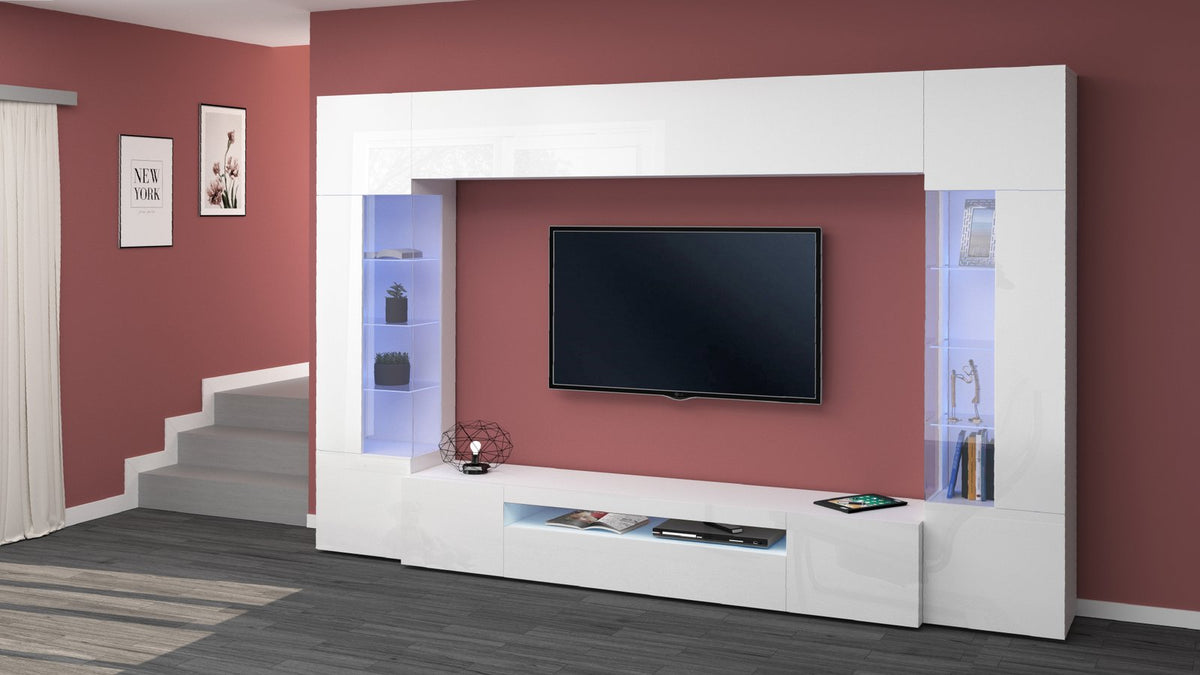 Parete attrezzata QUANTUM bianco lucido in soggiorno, vista di tre quarti con TV e vetrine illuminate #colore_Bianco Lucido