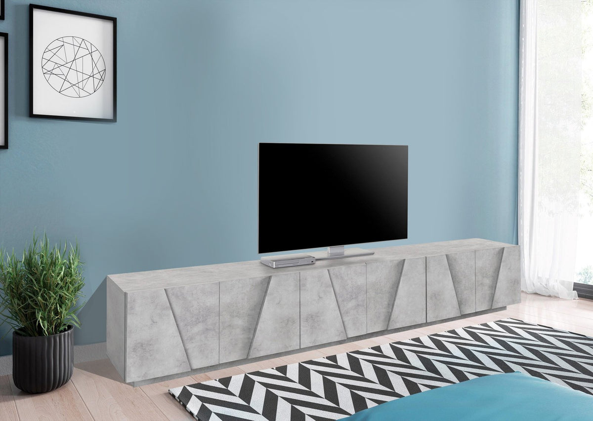 Porta TV PULSE cemento in stanza con parquet chiaro, televisore appoggiato e tappeto zigzag #colore_Cemento