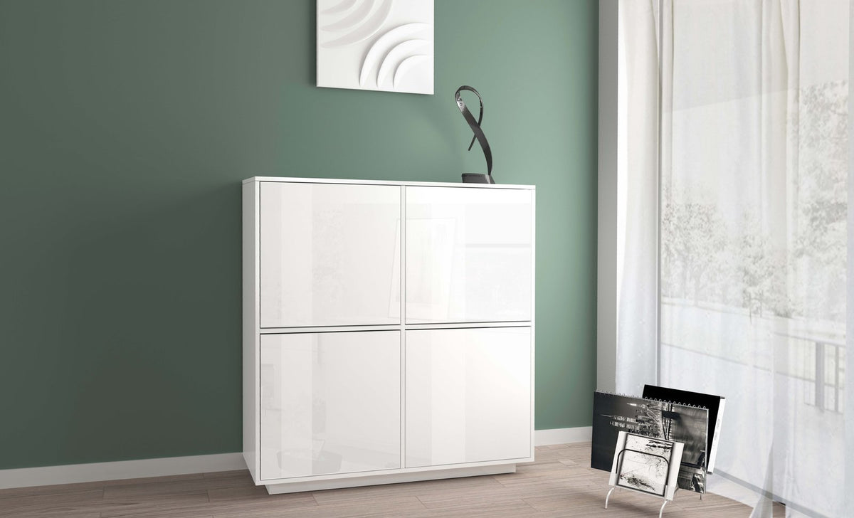 Credenza alta ENIGMA bianco lucido contro parete verde, con quadro bianco e finestra a destra