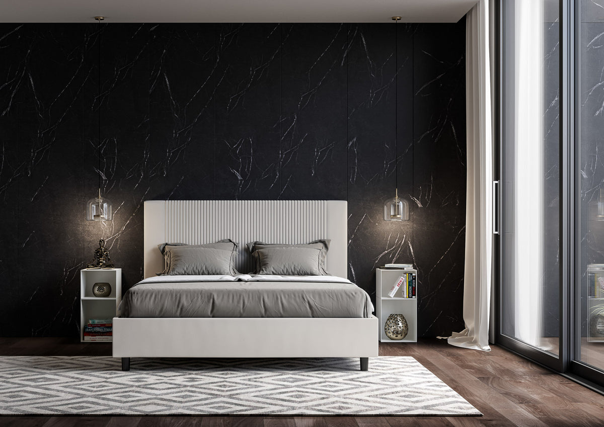 Letto GOYA bianco con testiera cannettata verticale, inquadrato frontalmente in una stanza arredata #colore_Bianco