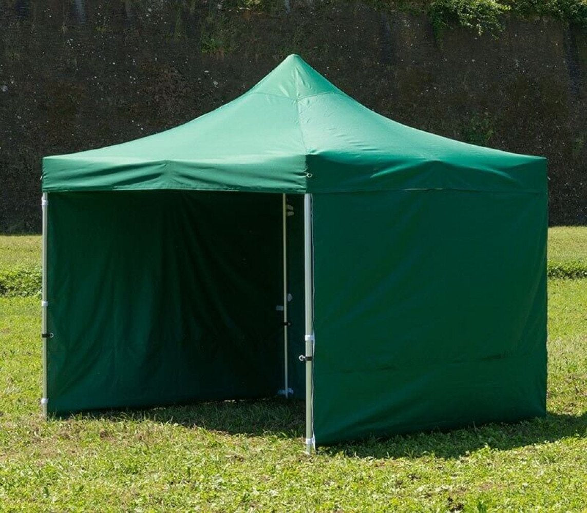 Gazebo HOLIDAY verde scuro montato su un prato con pareti laterali e una parete centrale aperta