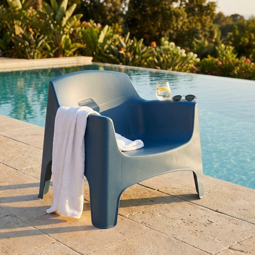 Poltrona IBIZA blu con braccioli e schienale avvolgente, bicchiere di limone appoggiato al bordo piscina