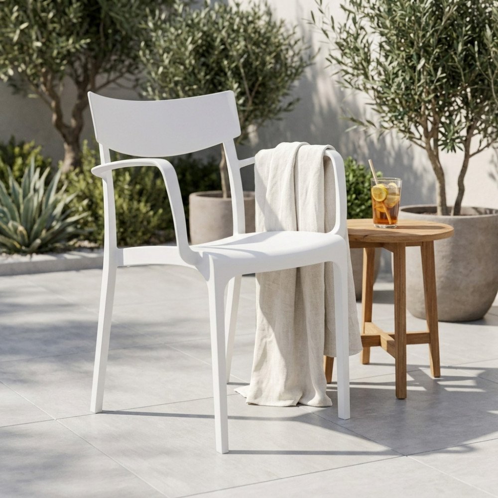 Poltrona da giardino CAMARGUE bianca con braccioli in polipropilene su pavimentazione chiara accanto a un tavolino