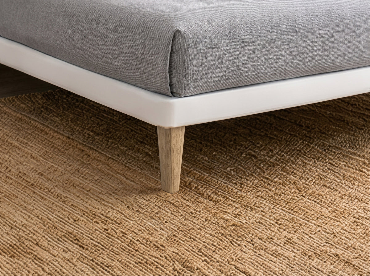Dettaglio della struttura bianca del letto SOFT bianco con gamba conica in legno su tappeto beige #colore_Bianco