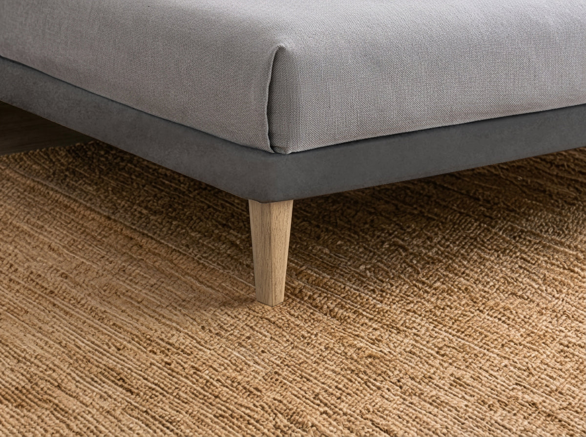 Dettaglio ravvicinato del letto FLAT grigio con piede conico su tappeto intrecciato #colore_Grigio