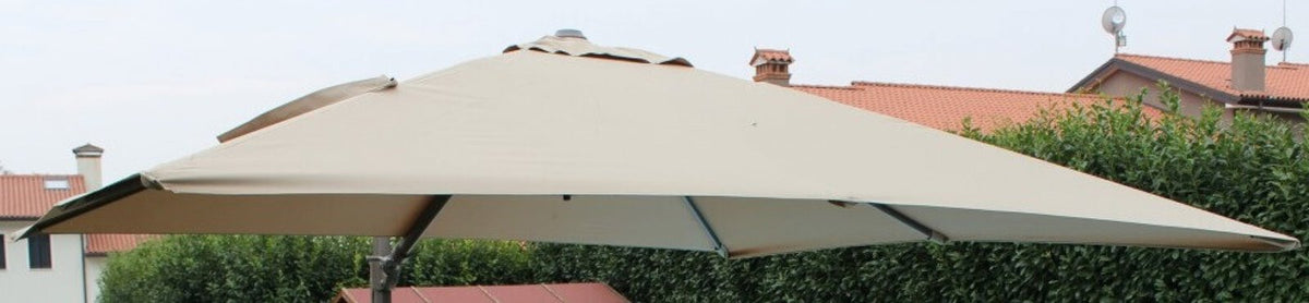 Telo di ricambio quadrato MERCURIO beige chiaro su ombrellone aperto in giardino, ripreso dal basso