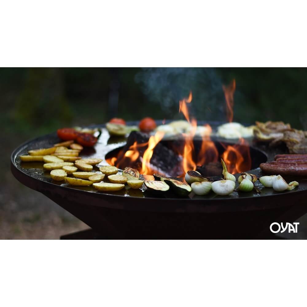 Barbecue OYA BBO 68 nero visto dall'alto mentre cuoce verdure e salsicce su fiamme alte