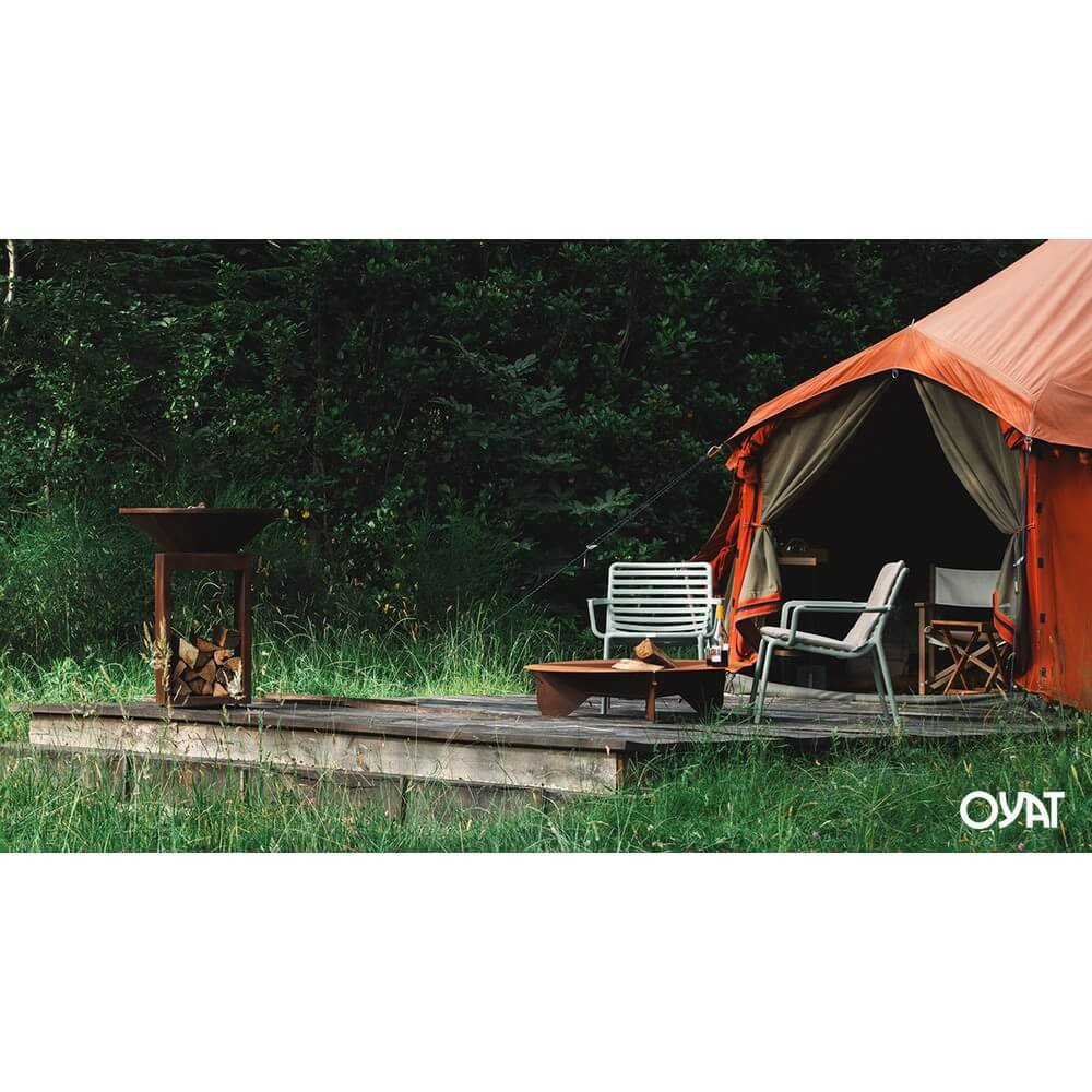 Barbecue OYA BBO 68 vista laterale con portalegna pieno di legna su pedana in giardino #colore_Nero